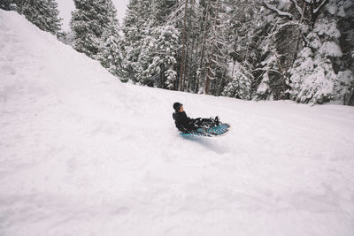 Young boy sledding quickly down a hill.