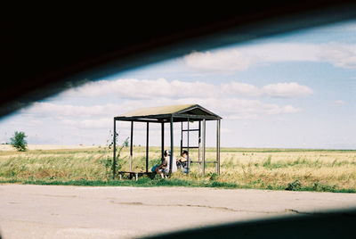 Gazebo on field by road against sky