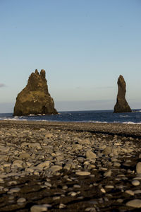 Rocks on sea shore against clear sky