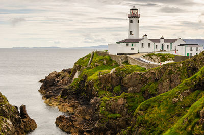 Lighthouse in sea against sky