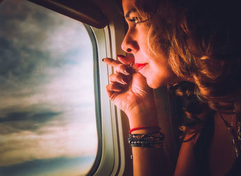 Woman looking through window against sky