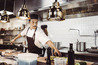 Manlig kock sträcker sig efter ingredienser i restaurangkök