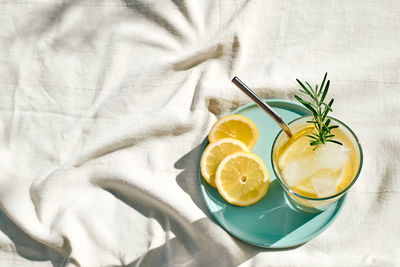 Summer refreshing lemonade drink or alcoholic cocktail with ice, rosemary and lemon slices on table