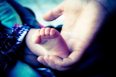 Low section of man touching baby feet