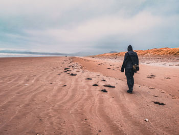 Rear view of man walking on beach