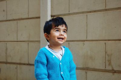 Smiling girl standing against wall