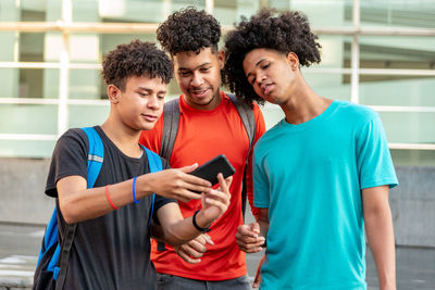 Multiethnic friends using mobile phone in the street