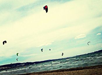 Hot air balloons flying over beach against sky