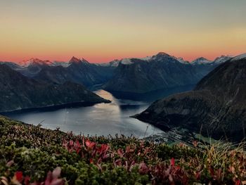 Scenic view of lake surrounded by mountains against sky during sunset