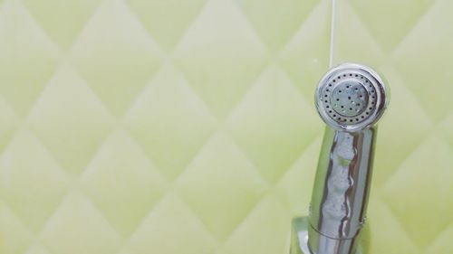 Close-up of shower by wall in bathroom