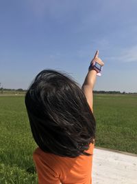 Rear view of girl pointing towards sky