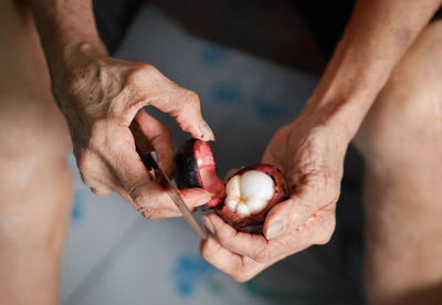 Cropped hands of man cutting fruit