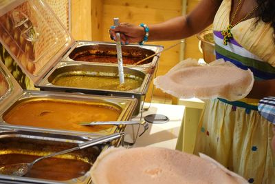 Midsection of woman taking food at buffet