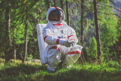 Curious astronaut crouching in forest