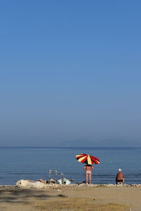 Beach umbrella by sea against clear sky