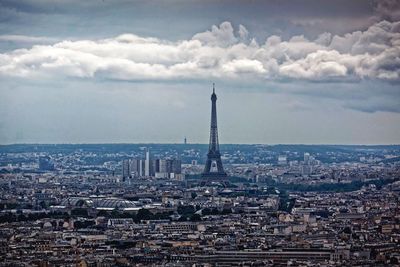 Eiffel tower amidst cityscape against sky