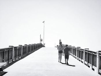 Men standing on railing against clear sky