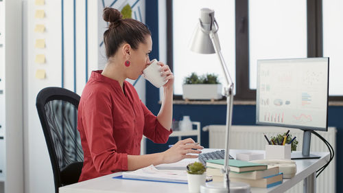 Young woman using mobile phone while sitting in office