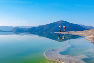 People on lake against sky