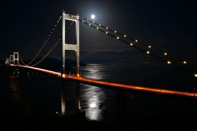 Illuminated suspension bridge over water at night