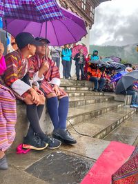 Woman sitting with umbrella in rain