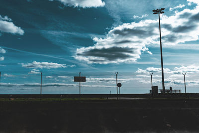 Low angle view of street lights on field against sky