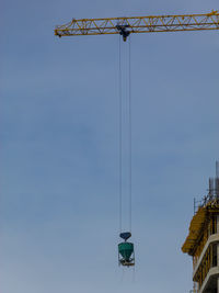 Low angle view of crane against clear blue sky