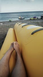 Low section of person on beach against sky