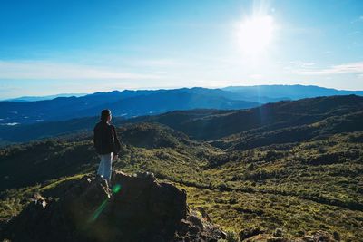 Man with umbrella on mountain against sky