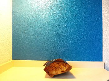Close-up of apple on table against blue wall