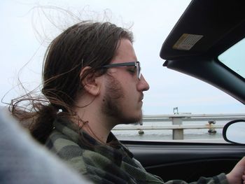 Portrait of young man looking through car. driving top down road trip