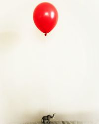 Red balloon flying against clear sky