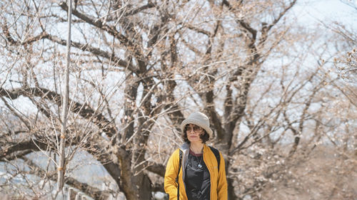 Portrait of young woman standing on tree