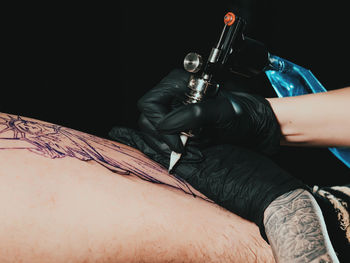 Young woman tattooing statue of liberty man on calf at parlor