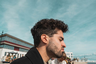 Portrait of young man looking away against sky