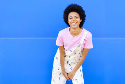 Young woman standing against blue background