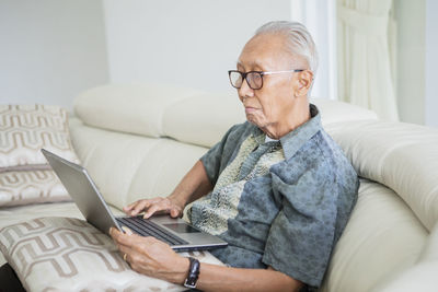 Senior man using laptop while sitting on sofa at home