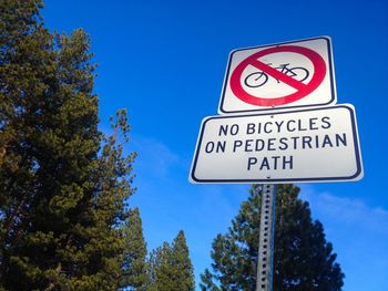 Low angle view of road sign against blue sky