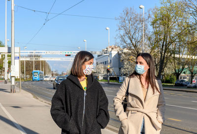 Two friends walking in city, wearing protective masks during corona virus epidemic, female, women.