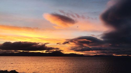 Scenic view of sea against dramatic sky during sunset
