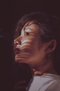 Close-up of young woman against black background