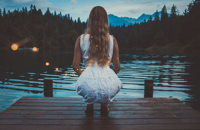 Rear view of women on pier over lake against sky