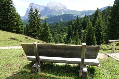 Empty bench on field against mountains