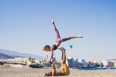 Upside down image of people on beach against clear sky