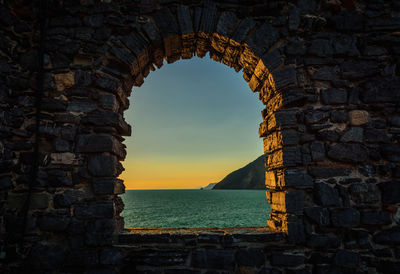 View of sea through arch window at sunset