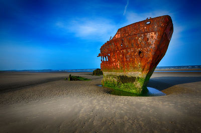 Abandoned shipwreck on beach against sky