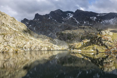 Scenic view of lake and mountains against cloudy sky