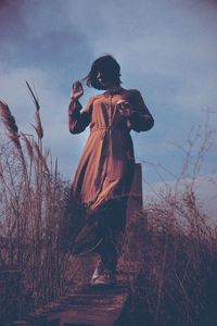 Full length of woman standing on field against sky