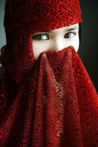 Close-up portrait of woman wearing red scarf against wall