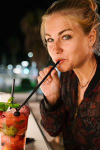 Close-up portrait of a young woman drinking glass